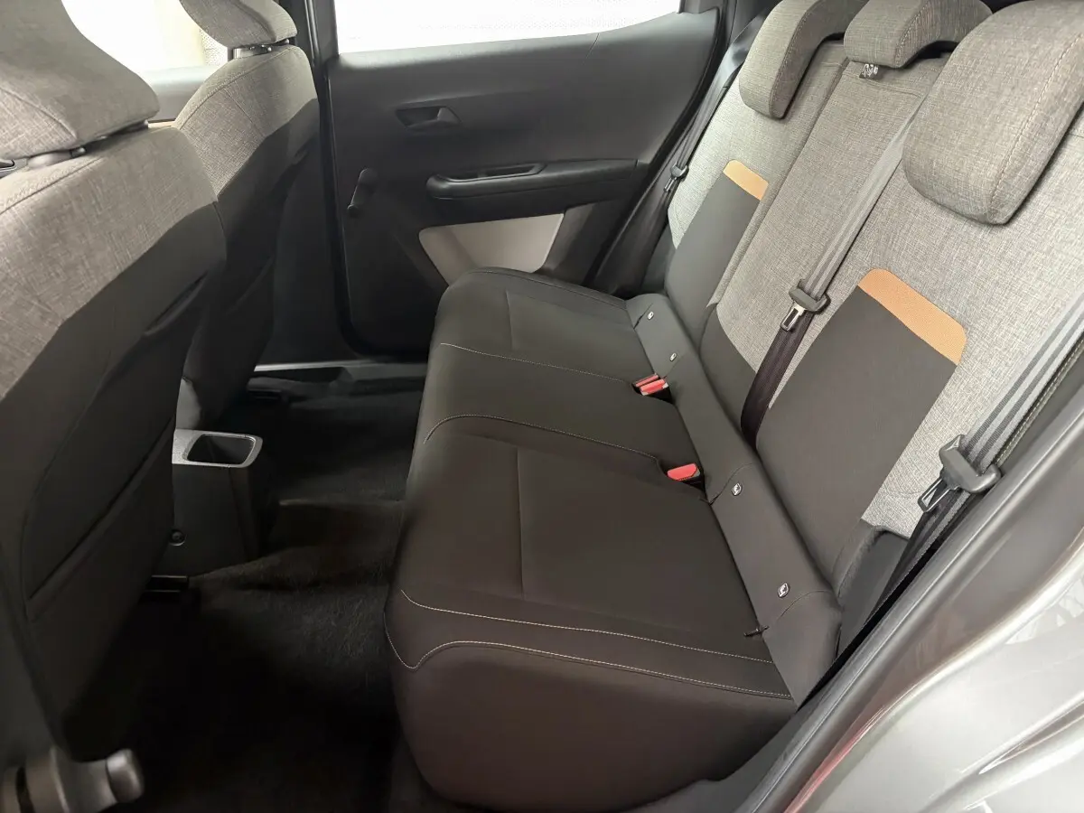 Vue intérieure côté droit des sièges arrière gris foncé et tissu clair avec détails orange de la Citroën C3 Aircross 2025 électrique.