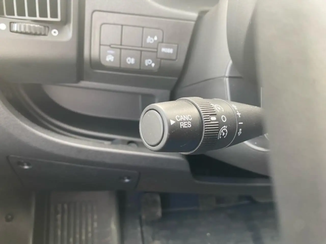 Gros plan sur la commande de régulateur de vitesse à gauche du volant dans l'habitacle du fourgon blanc Opel Movano.