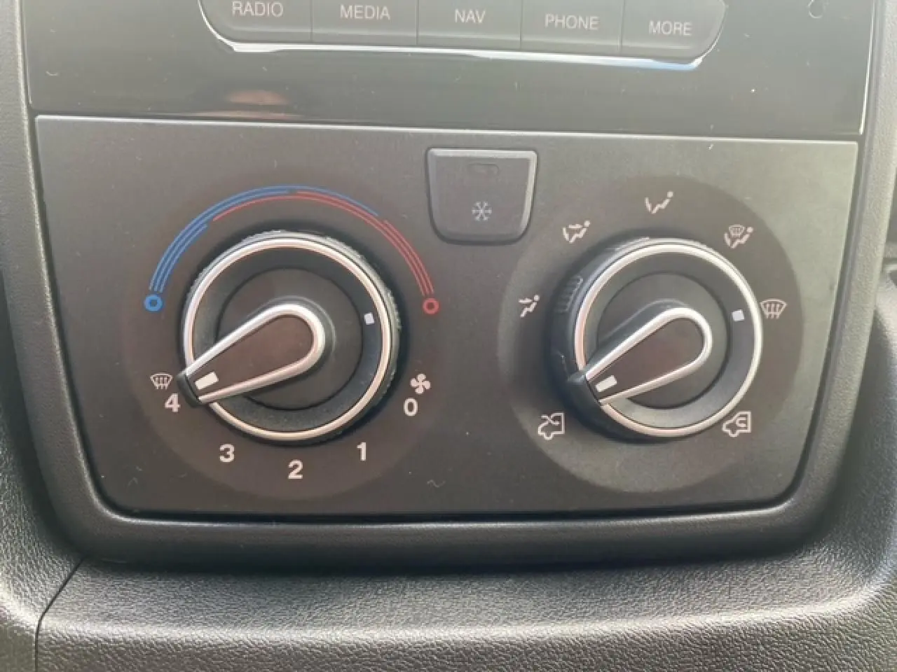Gros plan sur les commandes de climatisation du fourgon Opel Movano blanc, avec réglages de température et de ventilation visibles.