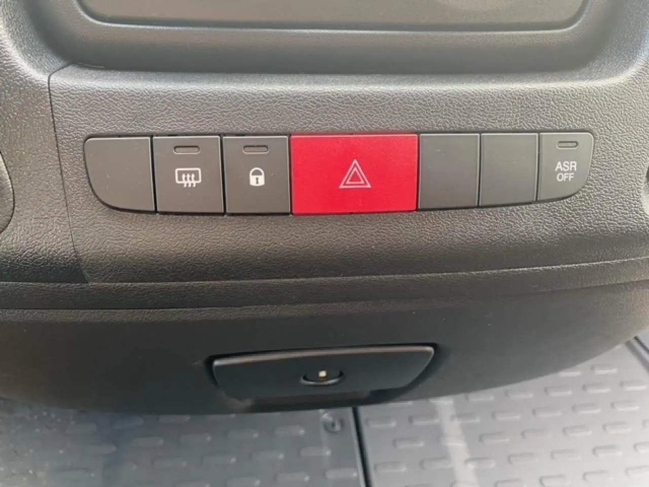 Gros plan sur les boutons de commande du tableau de bord noir de l'Opel Movano Fourgon blanc, avec bouton rouge de warning central.