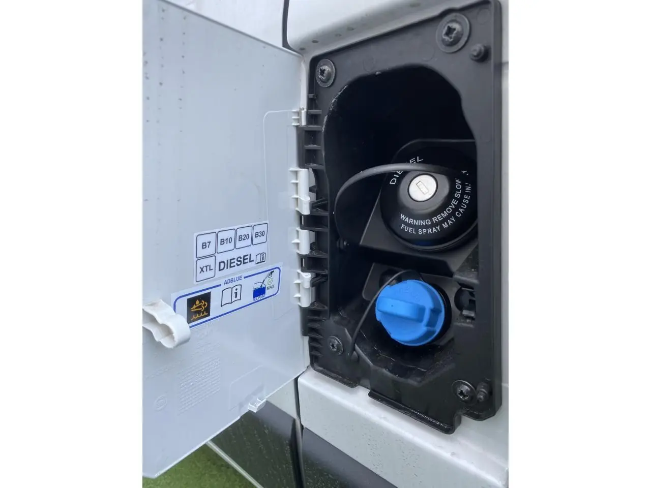 Gros plan sur la trappe à carburant blanche du fourgon Opel Movano Diesel, montrant bouchon noir diesel et bouchon bleu AdBlue.