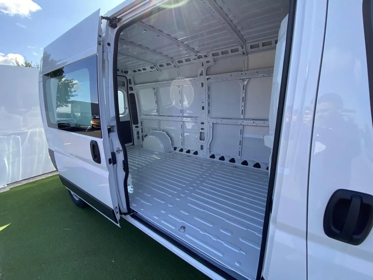 Vue latérale droite d'un Opel Movano Fourgon blanc avec porte coulissante vitrée ouverte dévoilant l'intérieur vide du compartiment de chargement.