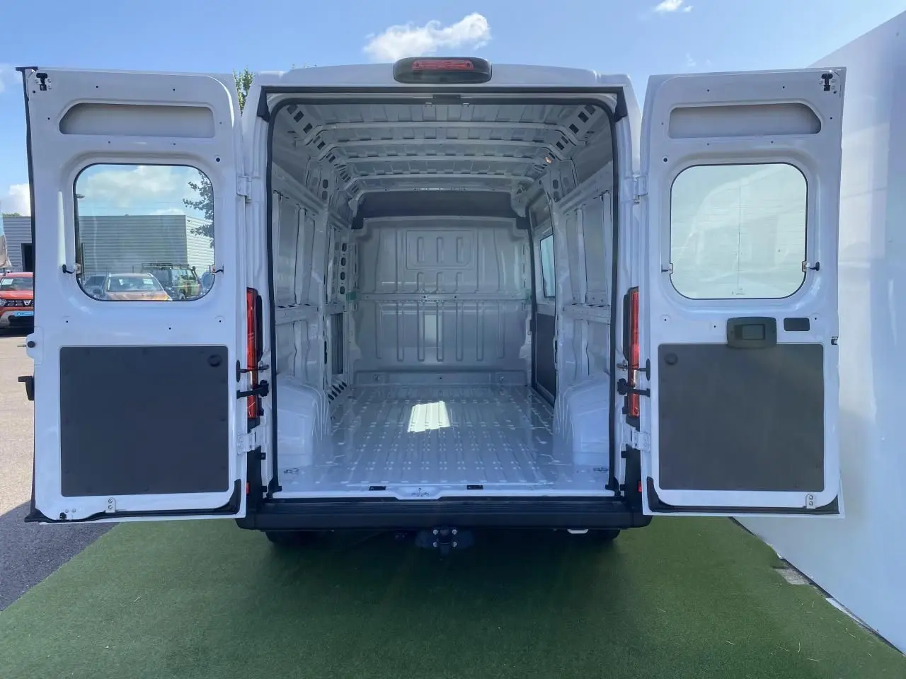 Vue arrière ouverte d'un Opel Movano Fourgon blanc 2023, montrant l'espace de chargement vide et le crochet d'attelage.