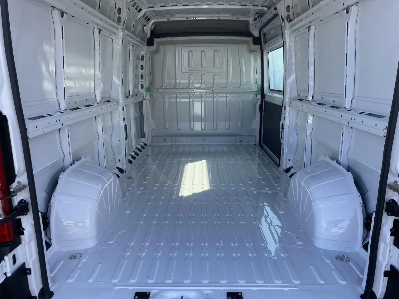 Intérieur vide du fourgon blanc Opel Movano L3H2 vu de l'arrière avec portes ouvertes et parois métalliques lisses.