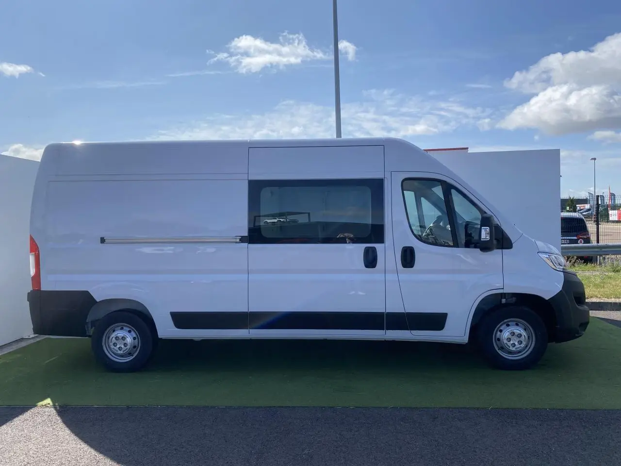 Profil droit d'un fourgon blanc Opel Movano L3H2 2023 avec porte latérale vitrée coulissante et roues acier.