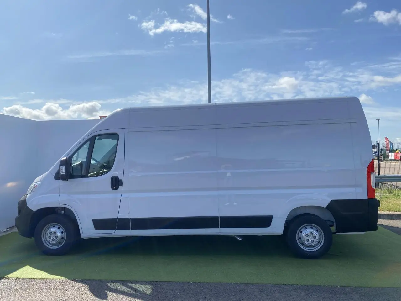 Vue latérale droite d'un fourgon blanc Opel Movano L3H2 2023 avec porte coulissante vitrée et crochet d'attelage.