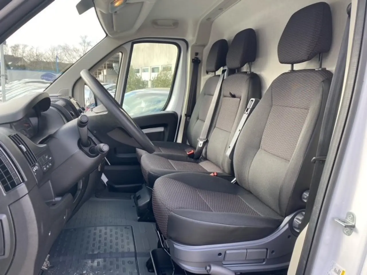 Vue intérieure côté conducteur de l'Opel Movano Fourgon blanc 2023 montrant les sièges avant et le tableau de bord.