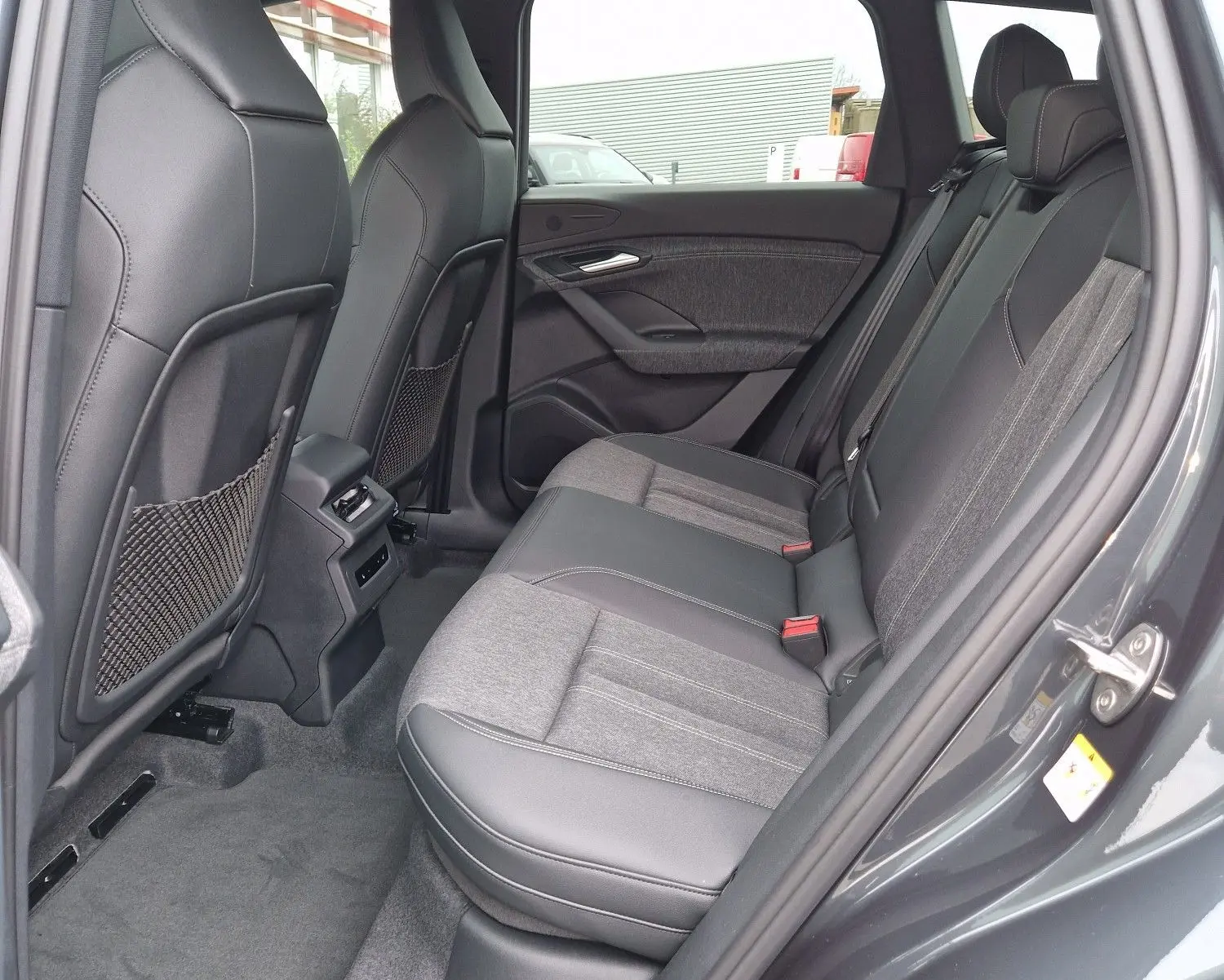Vue intérieure côté droit des sièges arrière en tissu et cuir gris d'un Audi Q6 e-tron Performance S-Line 2025.
