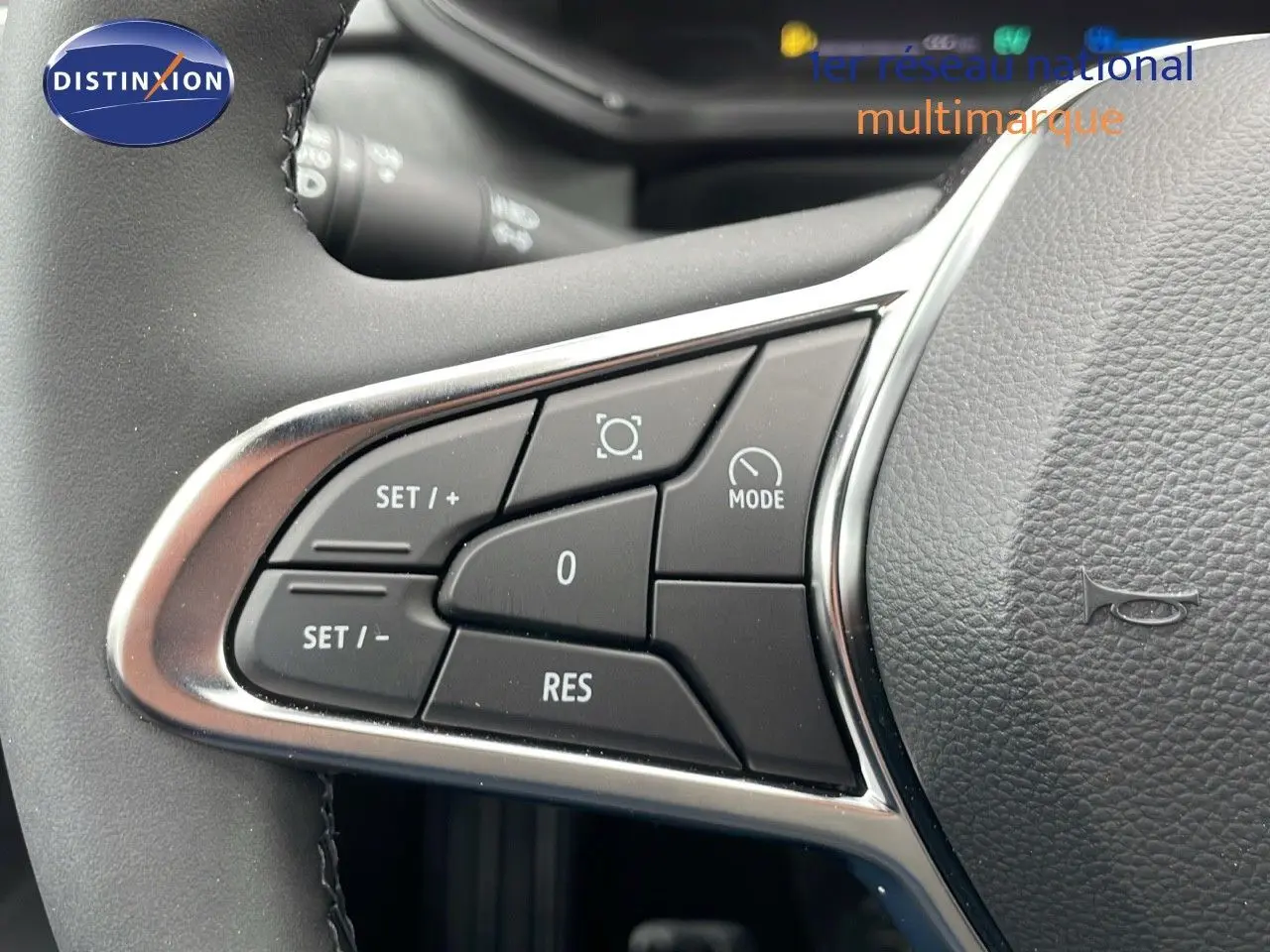 Gros plan sur les commandes du volant du Renault Captur E-Tech hybride, boutons noirs encadrés de chrome.