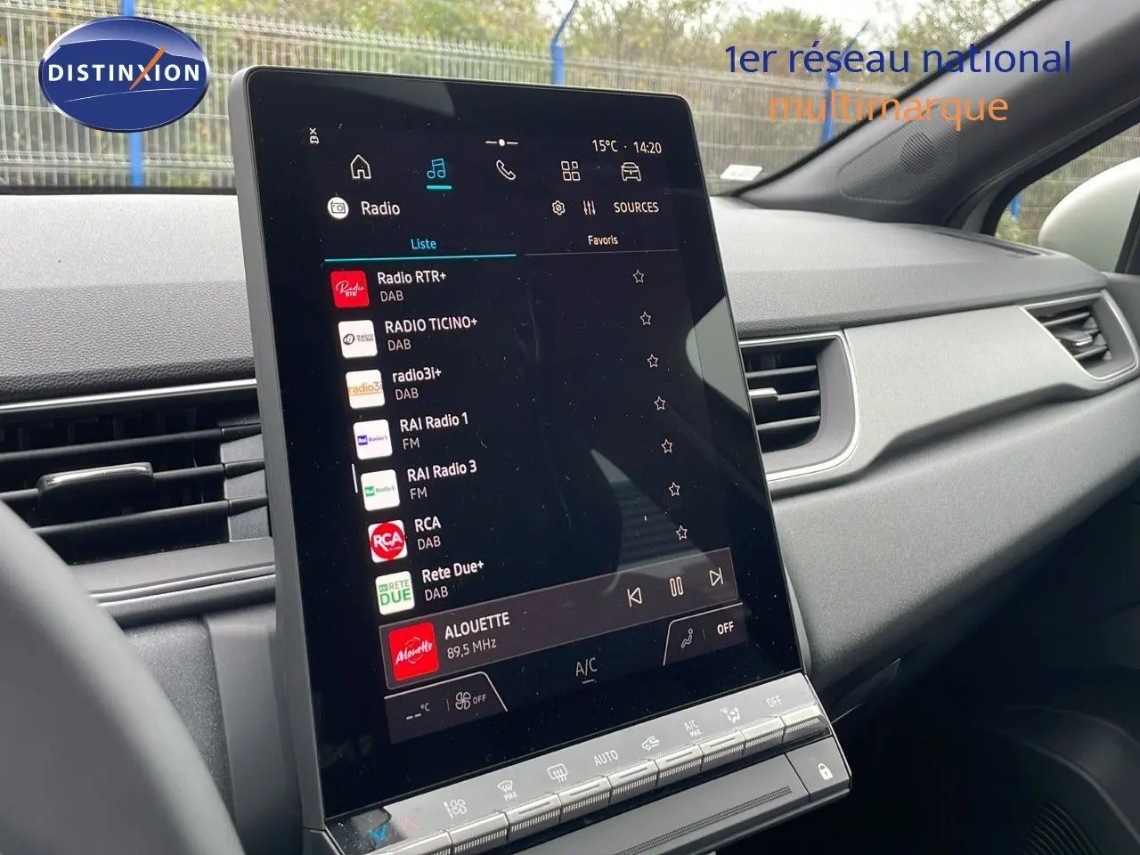 Écran tactile central allumé du tableau de bord du Renault Captur gris Rafale, affichant les stations radio numériques.