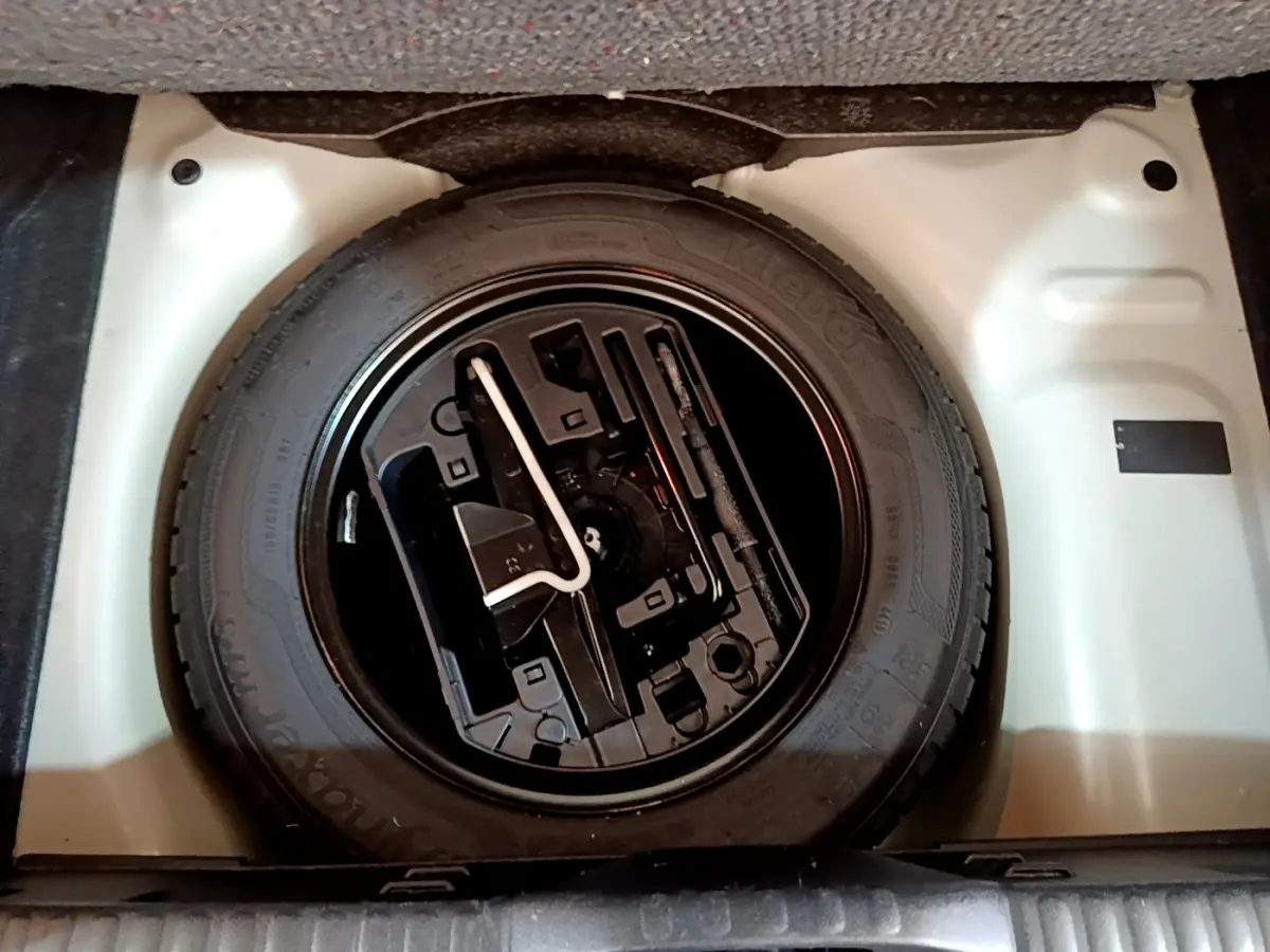 Gros plan sur la roue de secours noire dans le coffre blanc d'une Citroën C3 PureTech 110 Essence 2019