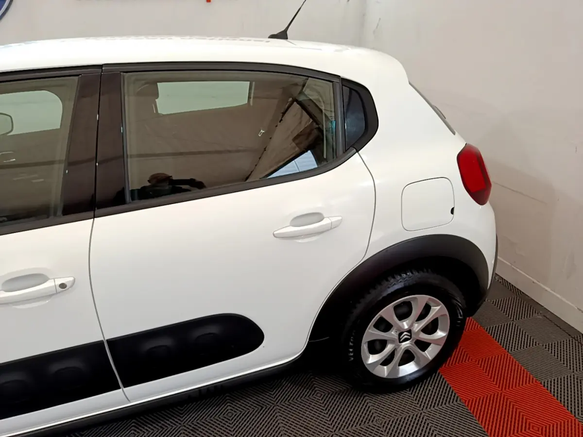 Vue latérale côté droit d'une Citroën C3 blanche avec protections noires sur les portières et jantes argentées.