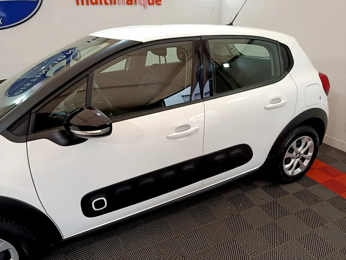 Vue de profil côté gauche d'une Citroën C3 blanche avec protections latérales noires et rétroviseur bicolore.