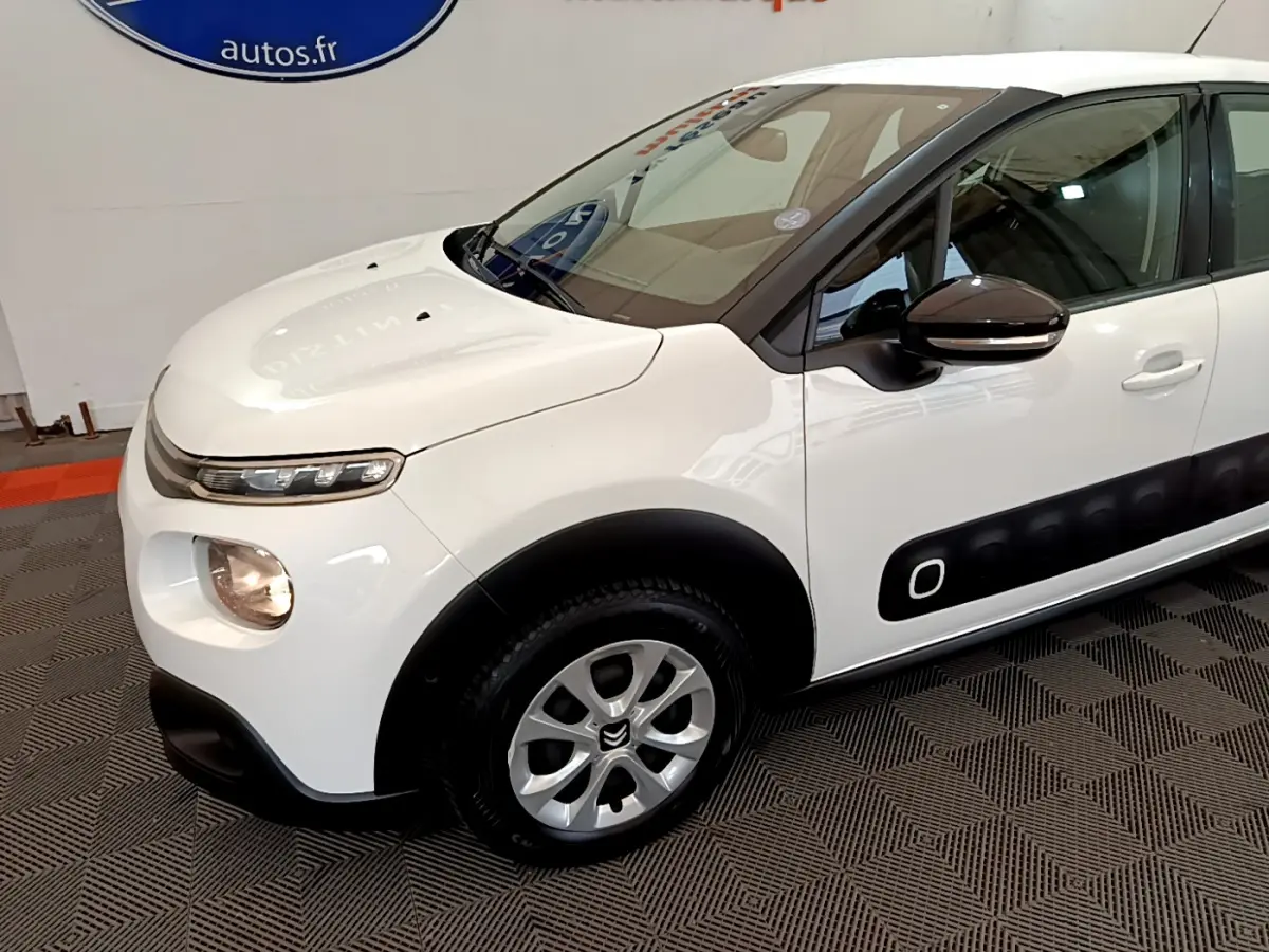 Vue 3/4 avant gauche d'une Citroën C3 blanche avec protections latérales noires et jantes alliage.