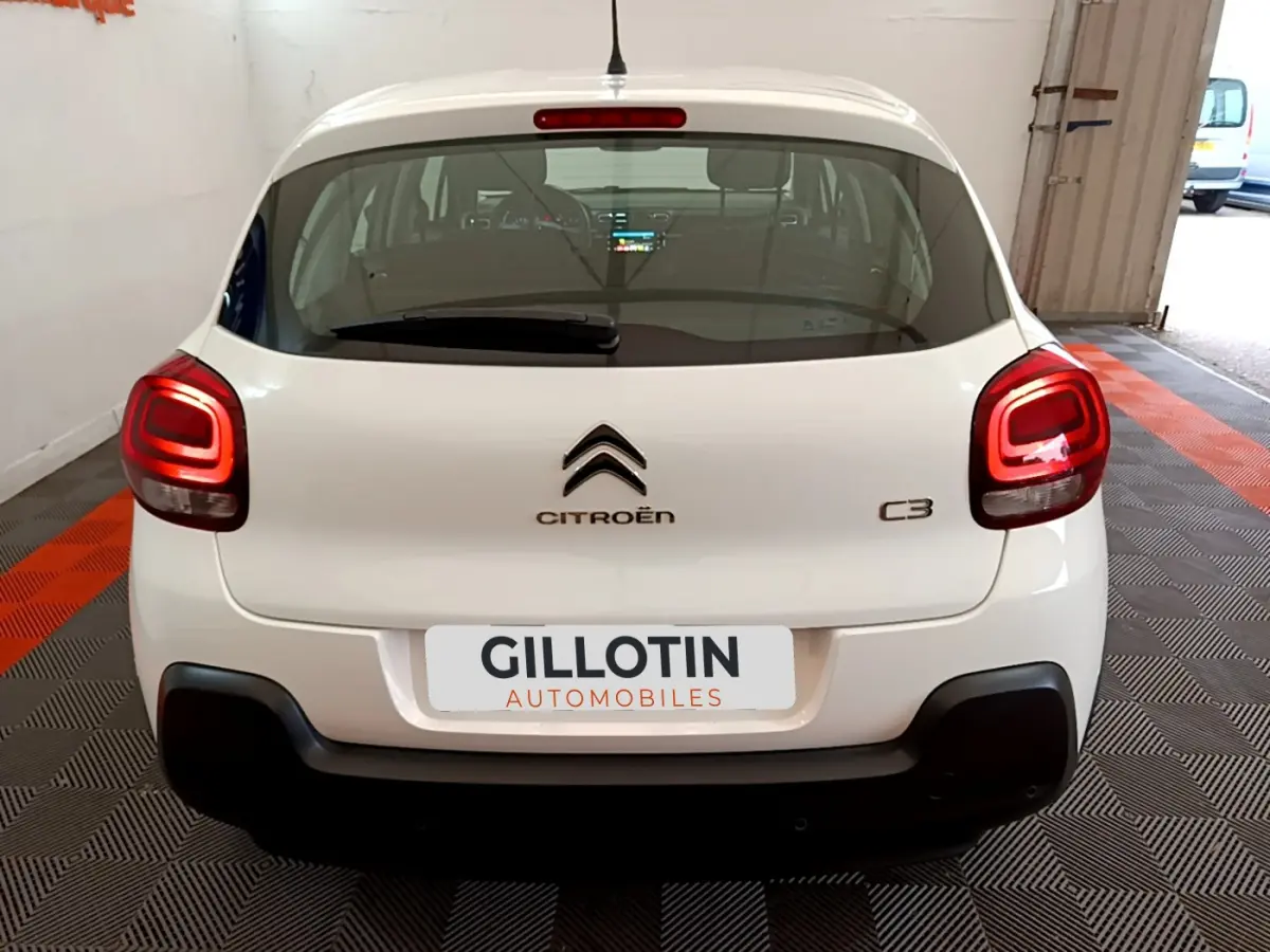 Vue arrière d'une Citroën C3 blanche de 2019 avec feux arrière allumés dans un garage.