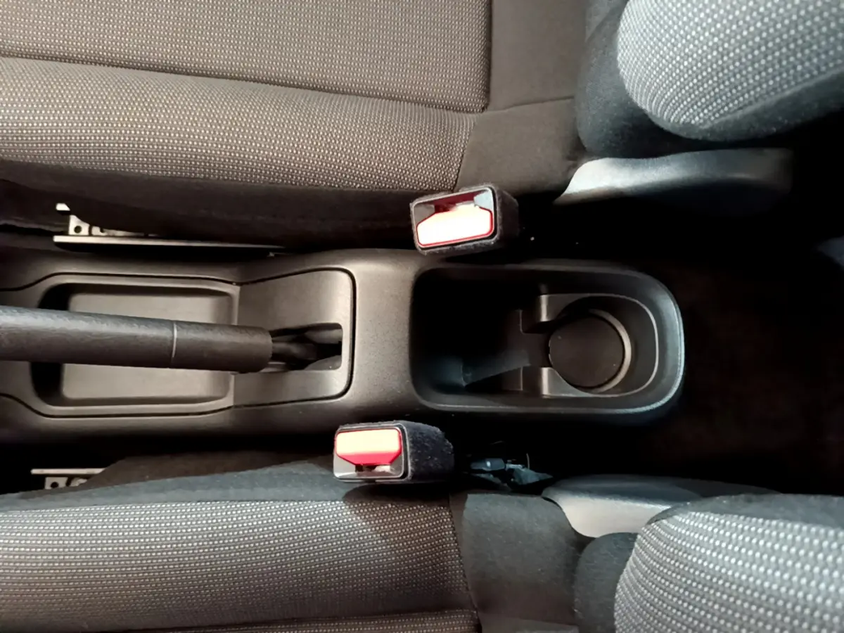 Vue plongeante sur la console centrale noire entre les sièges avant gris foncé de la Citroën C3 blanche de 2019.