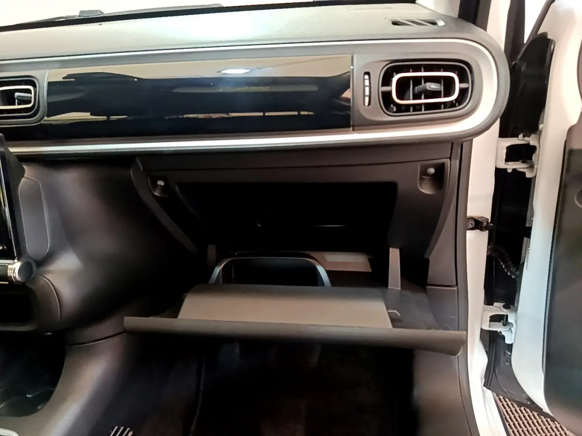 Intérieur de la Citroën C3 2019, vue côté passager sur la boîte à gants ouverte et la planche de bord noire brillante.