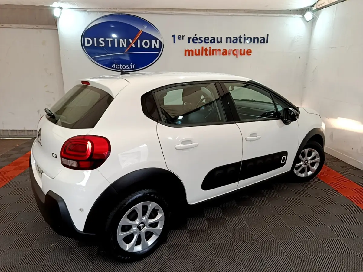 Citroën C3 blanche vue 3/4 arrière droit avec protections latérales noires et jantes argentées.