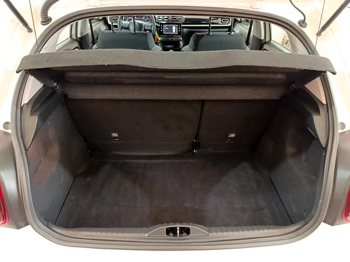 Coffre ouvert d'une Citroën C3 blanche vue de l'arrière, montrant l'espace de chargement et l'intérieur noir.