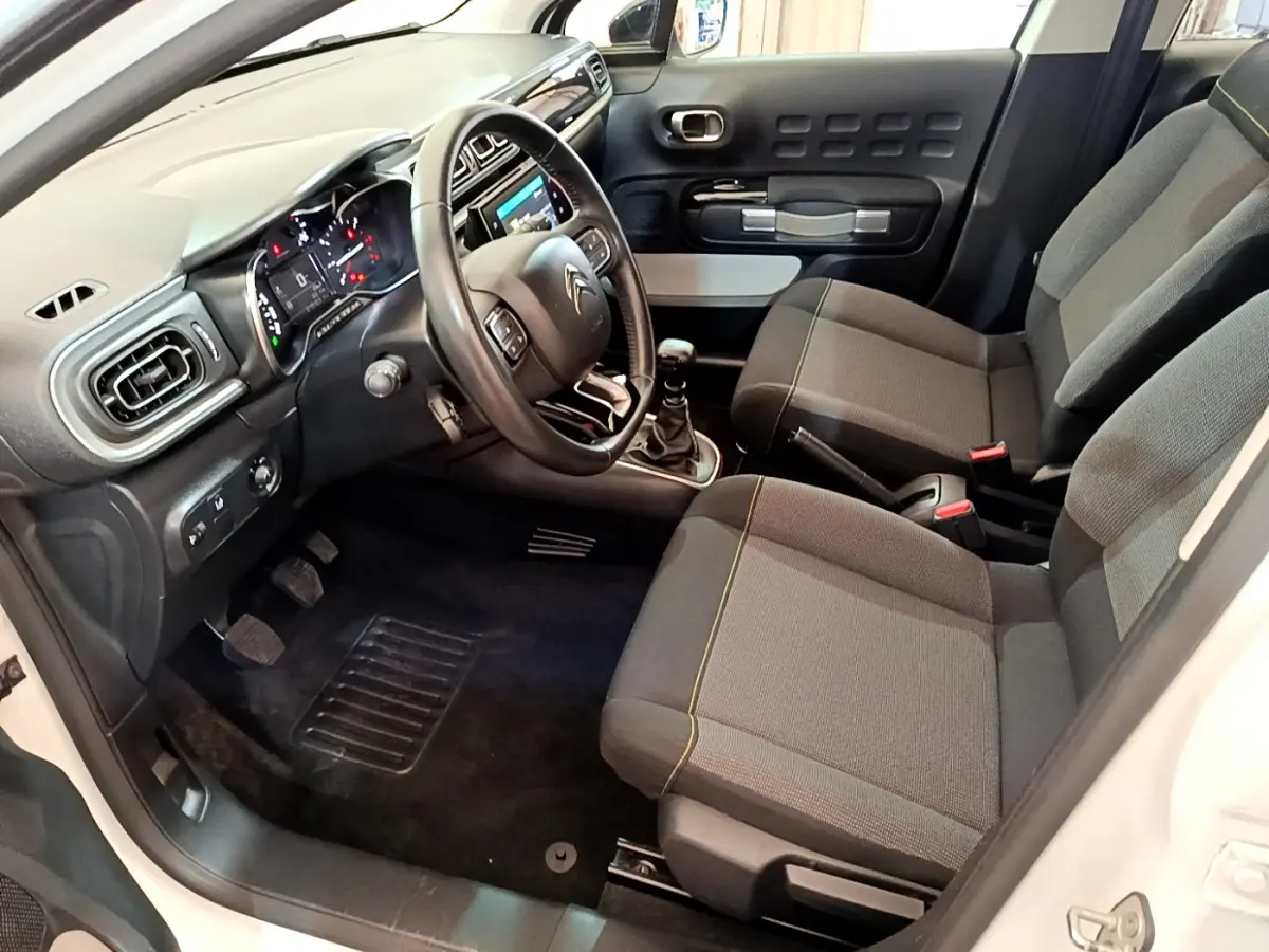 Intérieur avant droit d'une Citroën C3 blanche 2019, sièges gris, volant cuir et tableau de bord avec écran tactile.