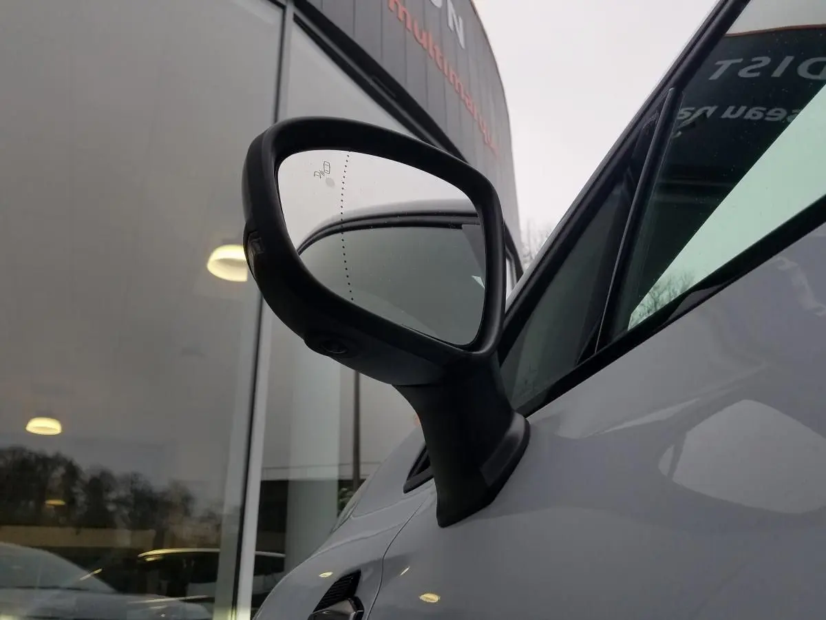 Rétroviseur côté gauche noir brillant du Renault Captur gris Rafale 2025, vue rapprochée sur la portière avant.