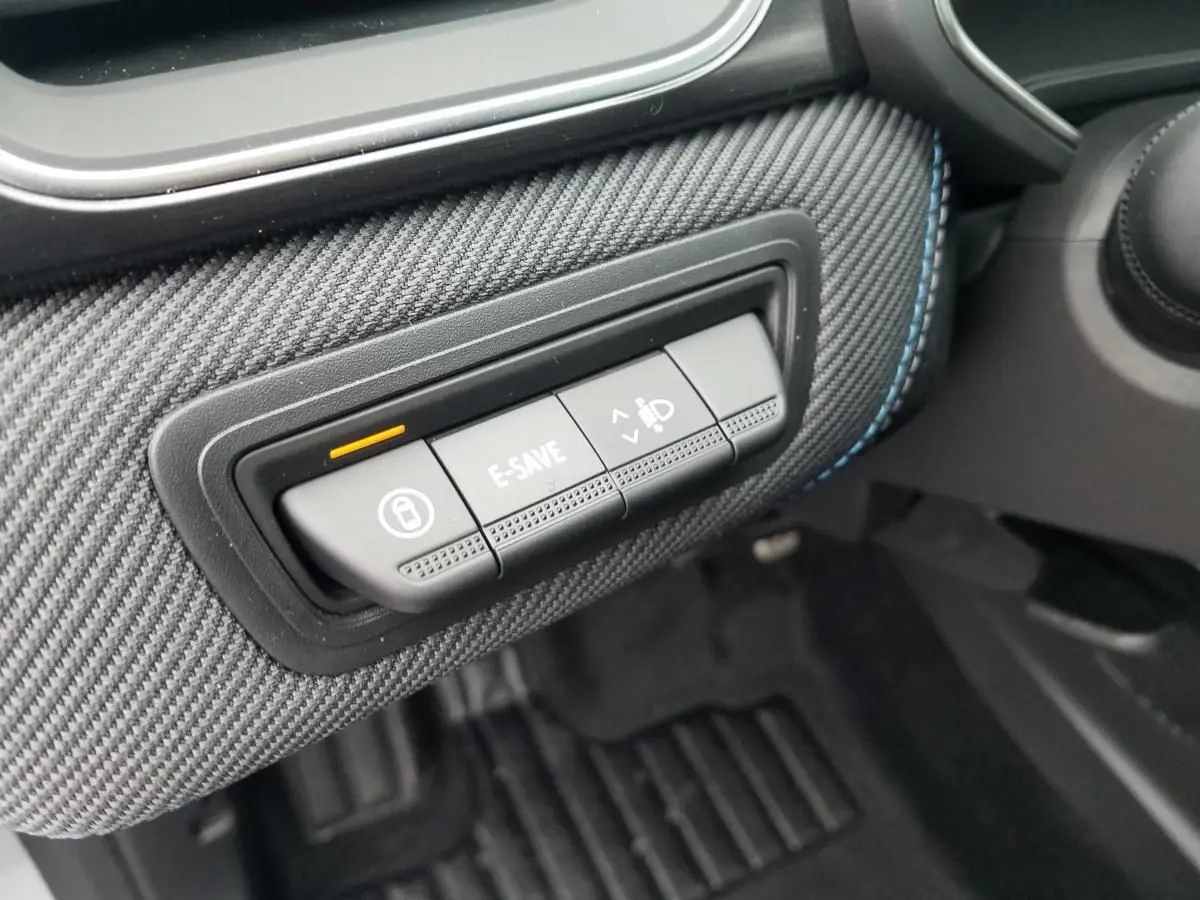 Gros plan sur les boutons de commande E-SAVE et réglage des phares sur la console côté conducteur du Renault Captur gris Rafale.
