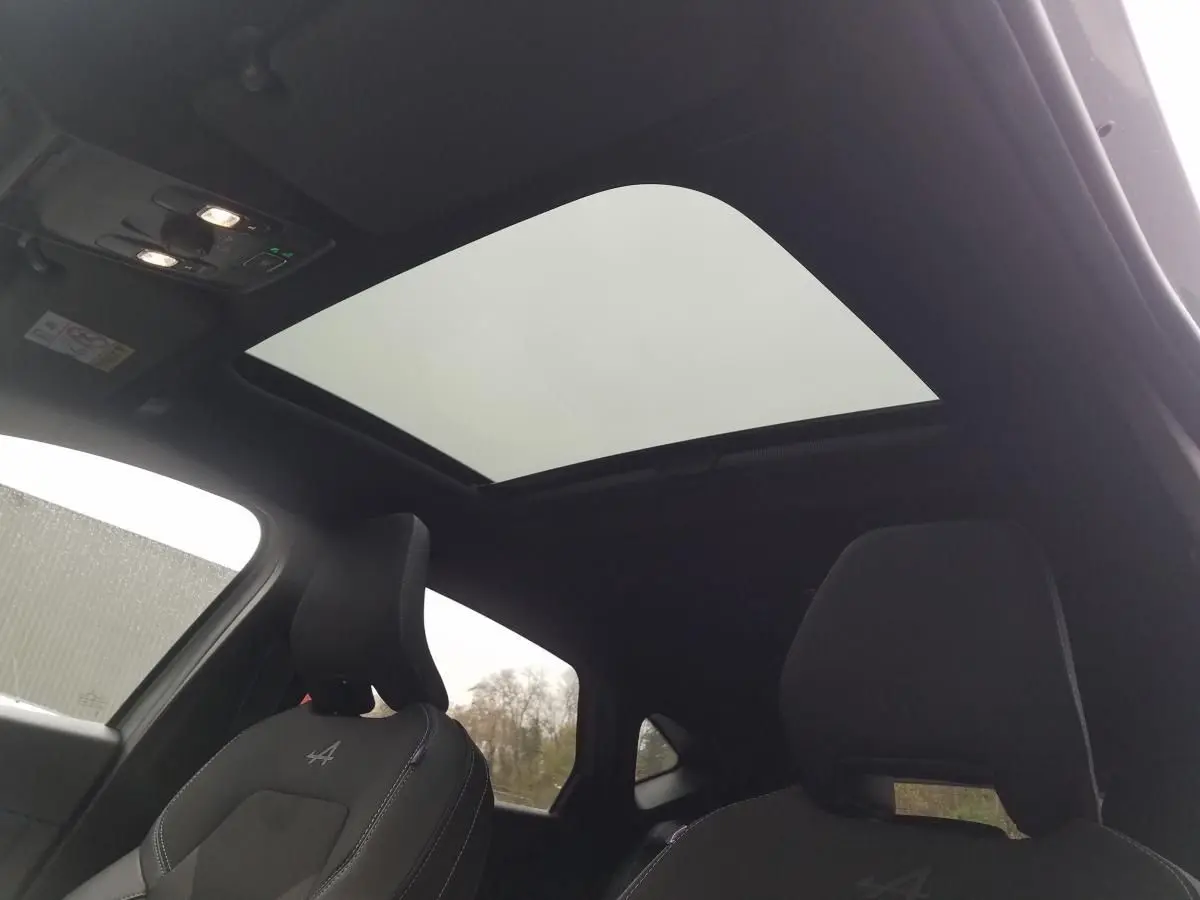 Intérieur du Renault Captur gris Rafale 2025 vu de l'arrière, avec toit ouvrant panoramique et sièges noirs Alpine.