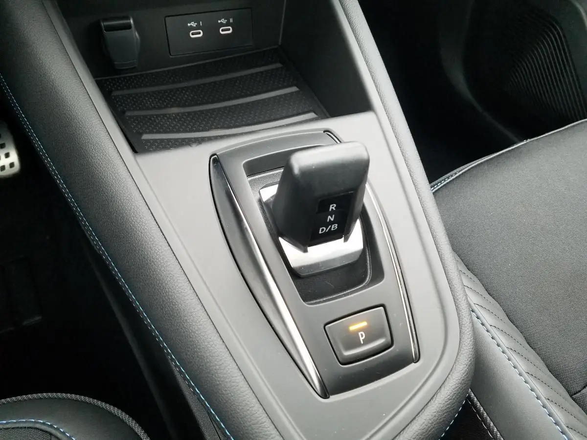 Gros plan sur la console centrale du Renault Captur 2025 avec levier de vitesses automatique et surpiqûres bleues.