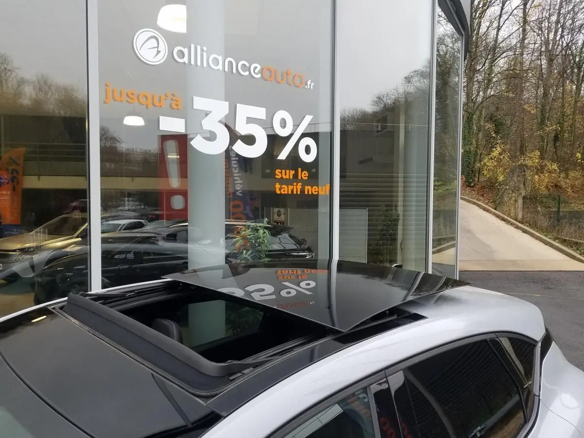 Toit ouvrant électrique ouvert sur le côté gauche d'un Renault Captur gris Rafale avec coques de rétroviseurs noires.