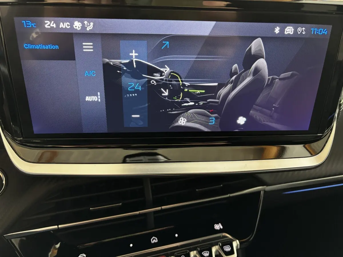 Écran tactile central de la Peugeot 208 Hybrid gris clair montrant la commande de climatisation et l'intérieur du véhicule.