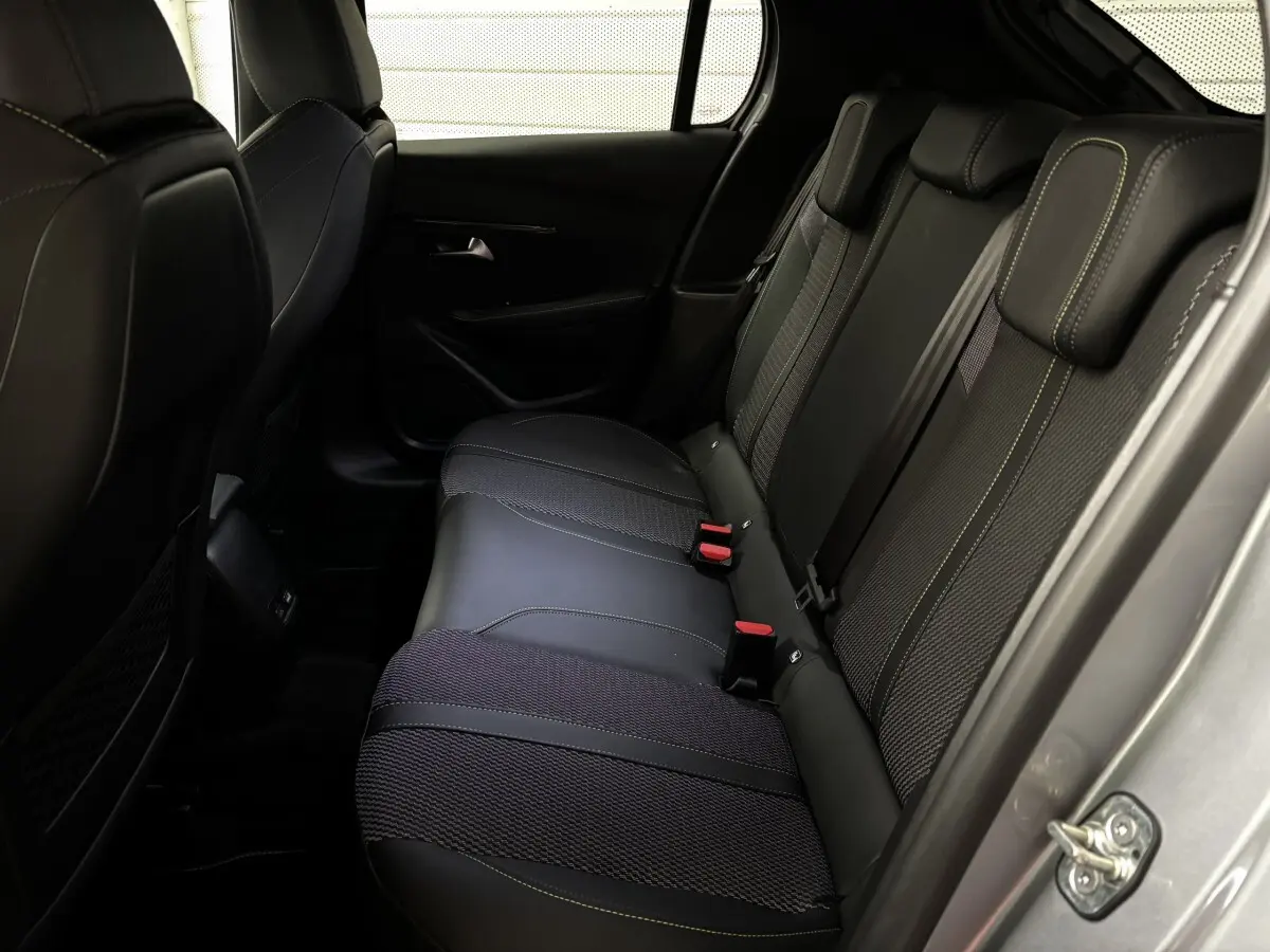 Vue intérieure côté arrière droit de la banquette arrière en tissu et cuir noir avec surpiqûres jaunes du Peugeot 208 Hybrid 110 e-DCS6 GT gris clair.