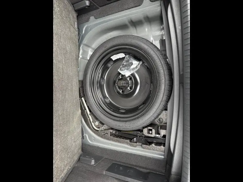 Vue rapprochée de la roue de secours noire dans le coffre du CUPRA Formentor bleu 2025, entourée d’outils de bord.