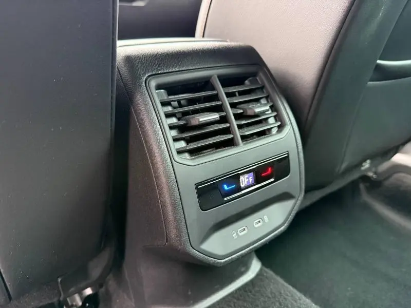 Vue rapprochée de la console arrière noire avec bouches d'aération et commandes climatisation du CUPRA Formentor bleu.