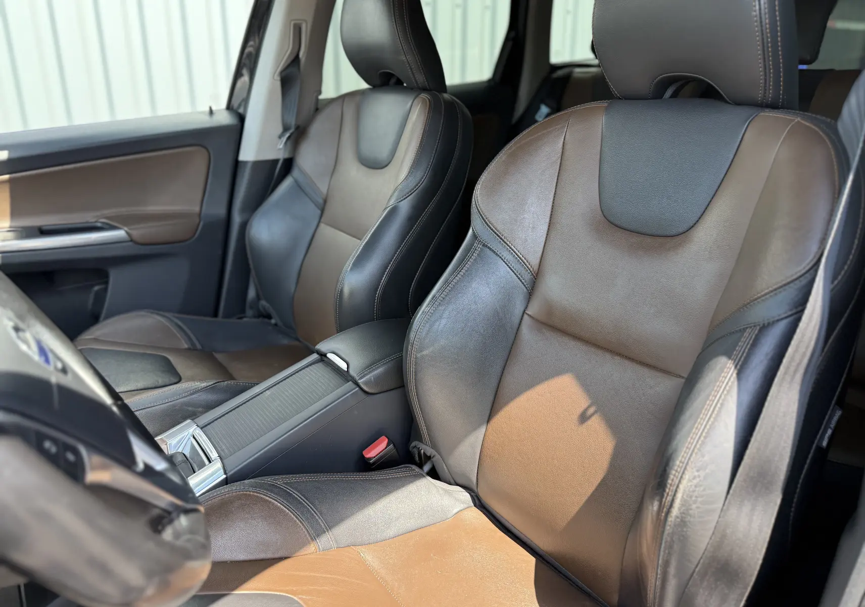 Vue rapprochée des sièges avant en cuir bicolore marron et noir du Volvo XC60 2016, côté conducteur et passager.