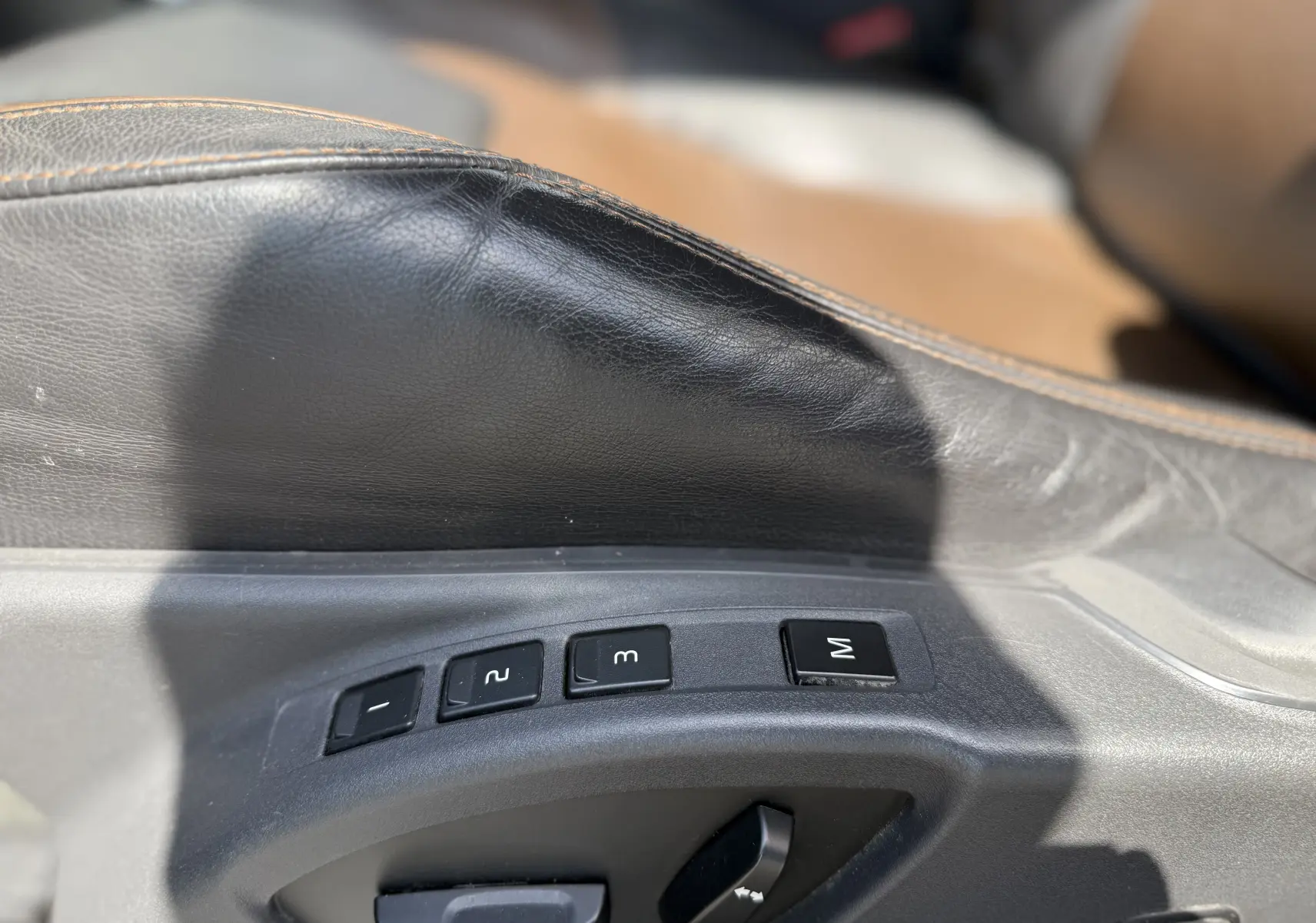Détail des commandes de réglage mémoire des sièges en cuir noir sur le côté gauche d’un Volvo XC60 gris foncé 2016.