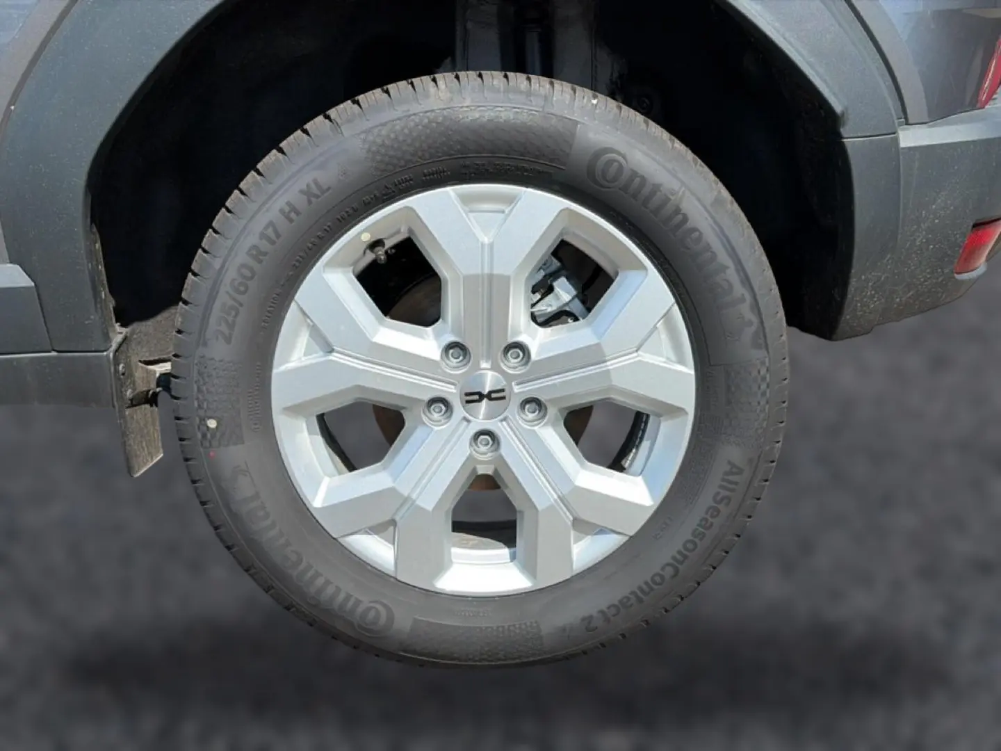 Gros plan sur la roue arrière droite du Dacia Duster gris schiste, jante alu à design hexagonal.