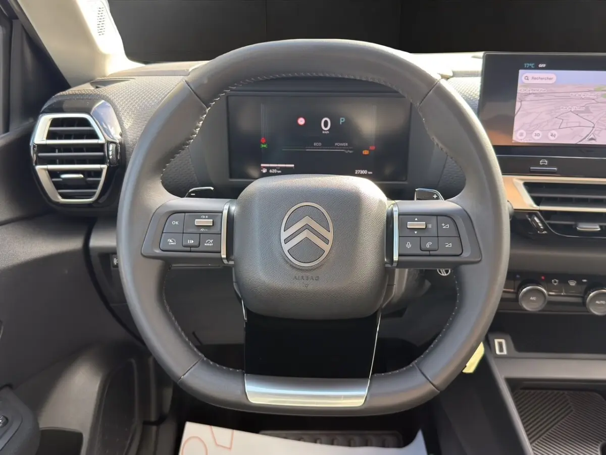 Vue centrée sur le volant cuir multifonctions et le tableau de bord numérique de la Citroën C4 hybride 2025.
