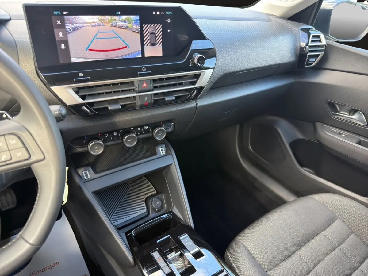 Vue intérieure côté passager de la Citroën C4 hybride 2025, tableau de bord avec écran tactile et console centrale noire.