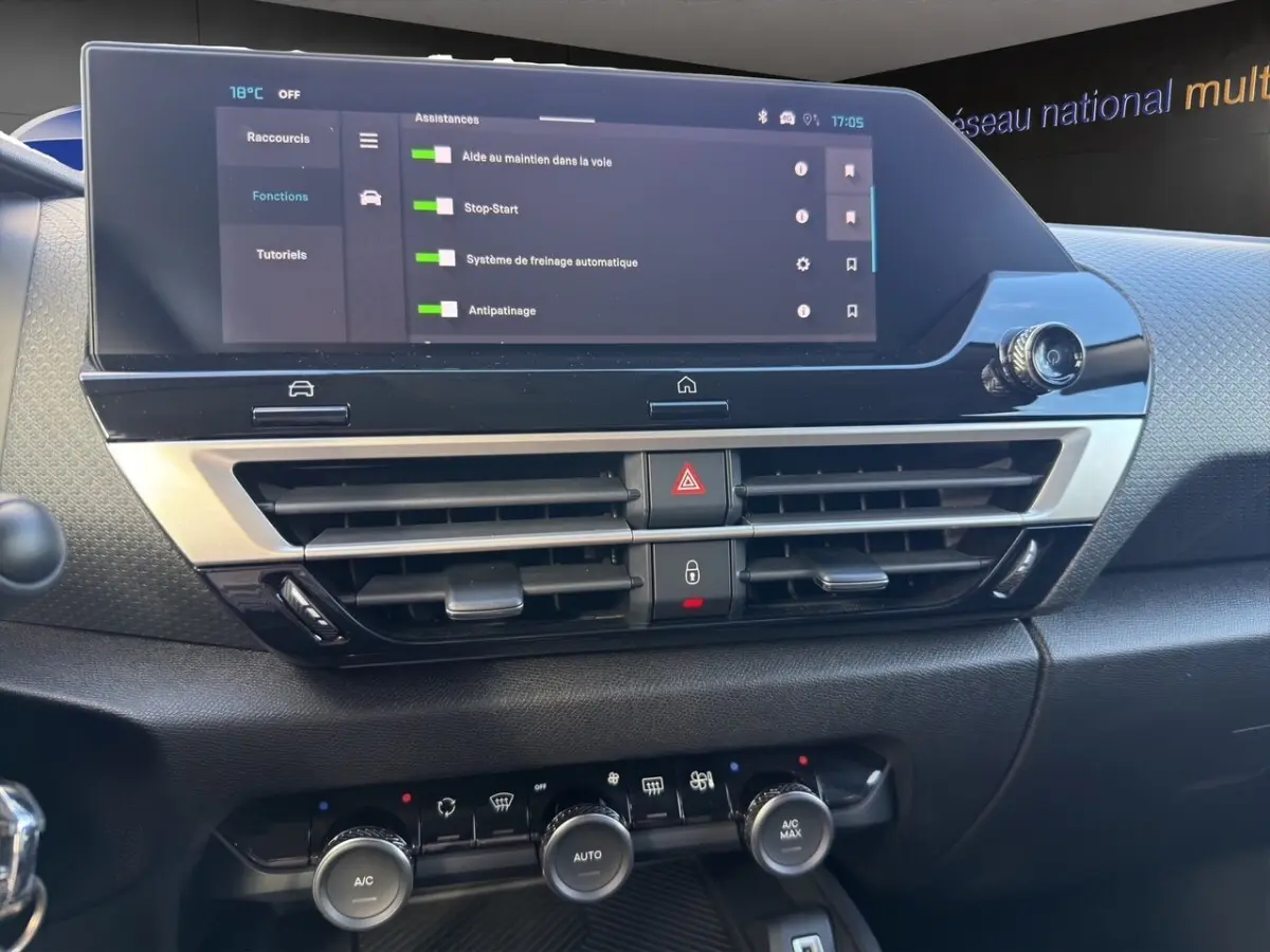 Vue rapprochée du tableau de bord central de la Citroën C4 hybride 2025, écran tactile et commandes climatisation visibles.