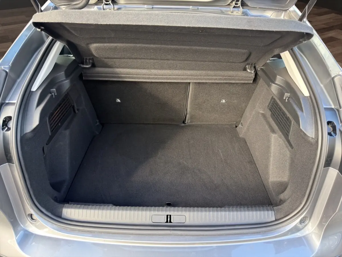 Coffre ouvert vu de l'arrière d'une Citroën C4 hybride gris foncé, montrant un espace de chargement propre et spacieux.