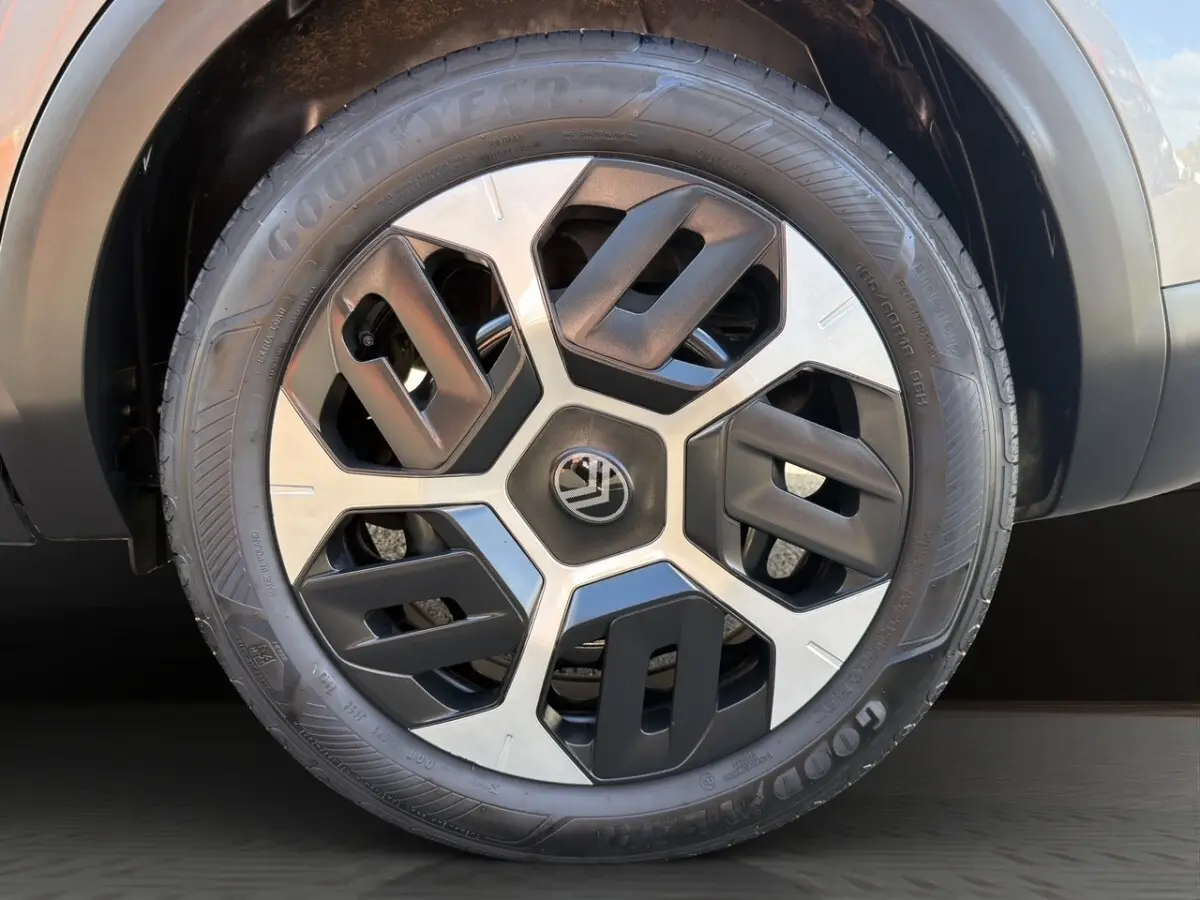 Gros plan sur la roue avant droite gris foncé d'une Citroën C4 hybride 2025 avec jante au design géométrique bicolore.
