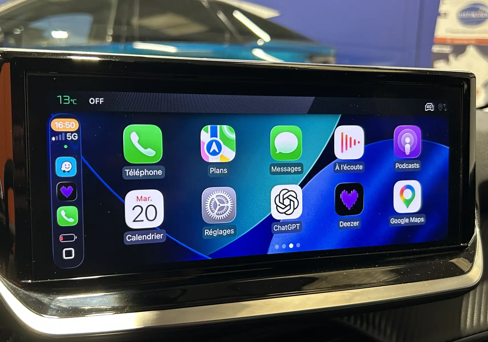 Écran tactile intérieur du Peugeot 208 II Turbo 100 Allure, affichant les applications connectées avec reflet d'une voiture grise en arrière-plan.
