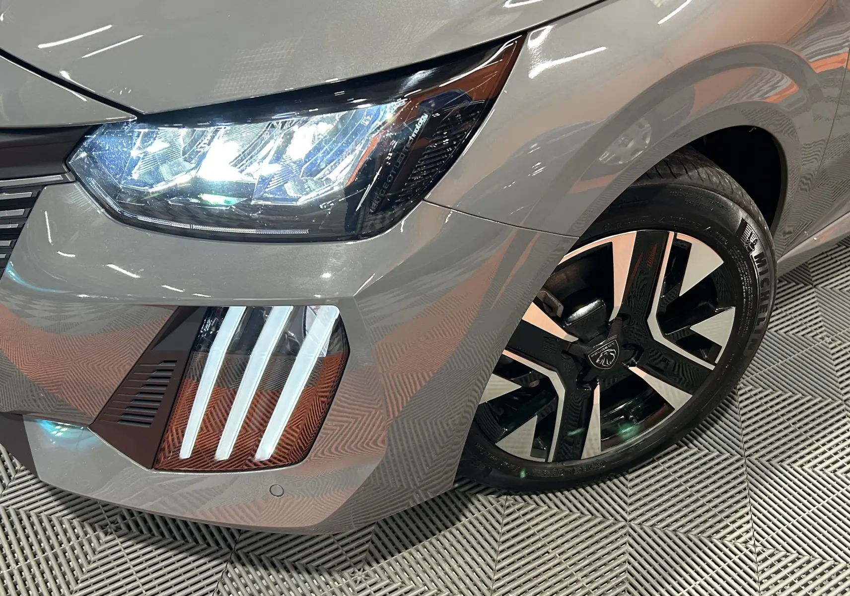 Gros plan sur l'avant droit gris Selenium du Peugeot 208 II Turbo 100 Allure avec phares LED et jante alliage noire et argent.