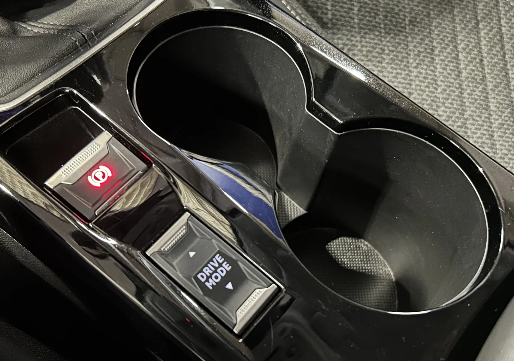 Gros plan sur la console centrale noire de la Peugeot 208 II avec bouton frein à main électronique et sélecteur Drive Mode.