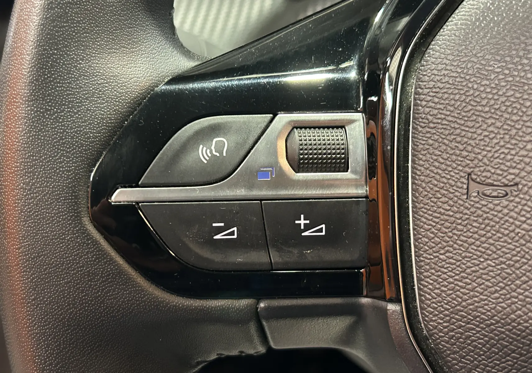 Gros plan sur les commandes de volume vocal sur le volant d’une Peugeot 208 gris Selenium, version 2025.