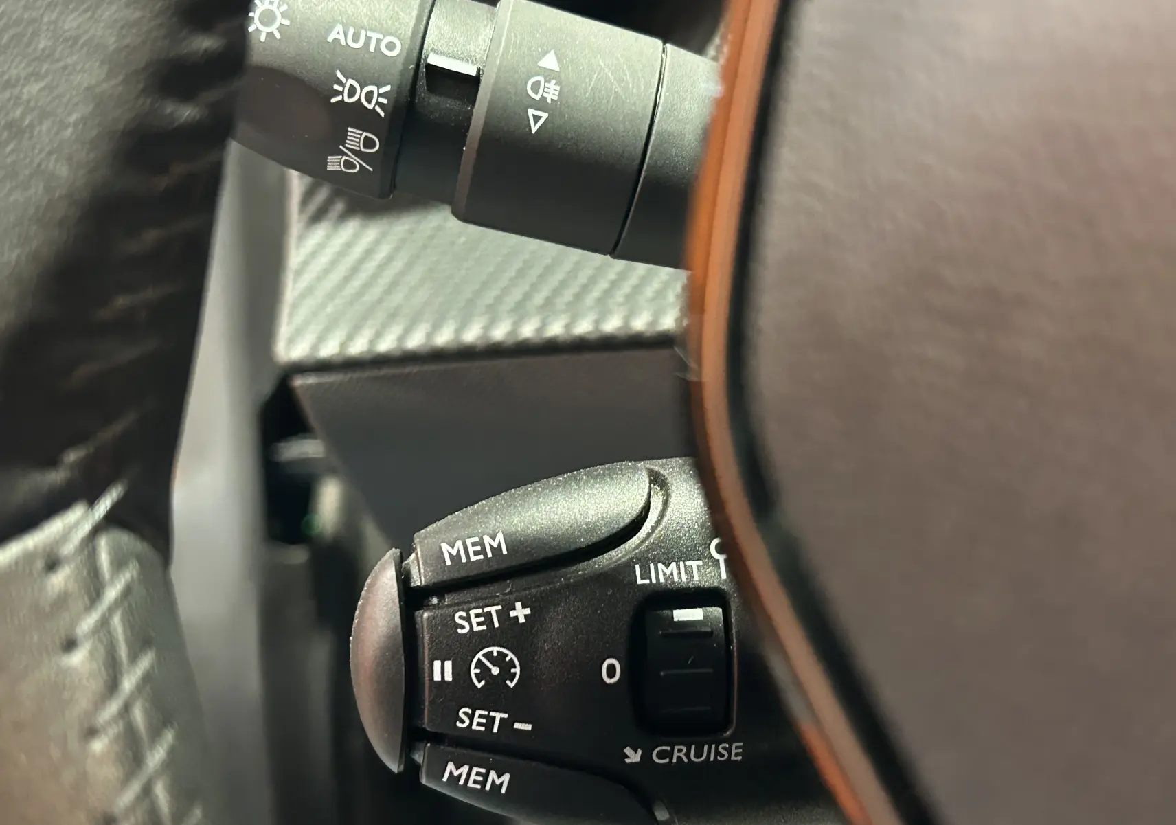 Gros plan sur les commandes de régulateur de vitesse au volant d'une Peugeot 208 gris Selenium, version 2025.