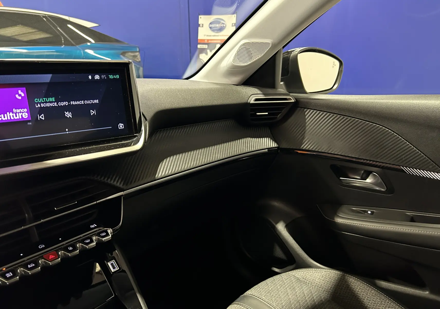 Intérieur côté passager de la Peugeot 208 gris Selenium, tableau de bord avec écran tactile et détails en carbone.