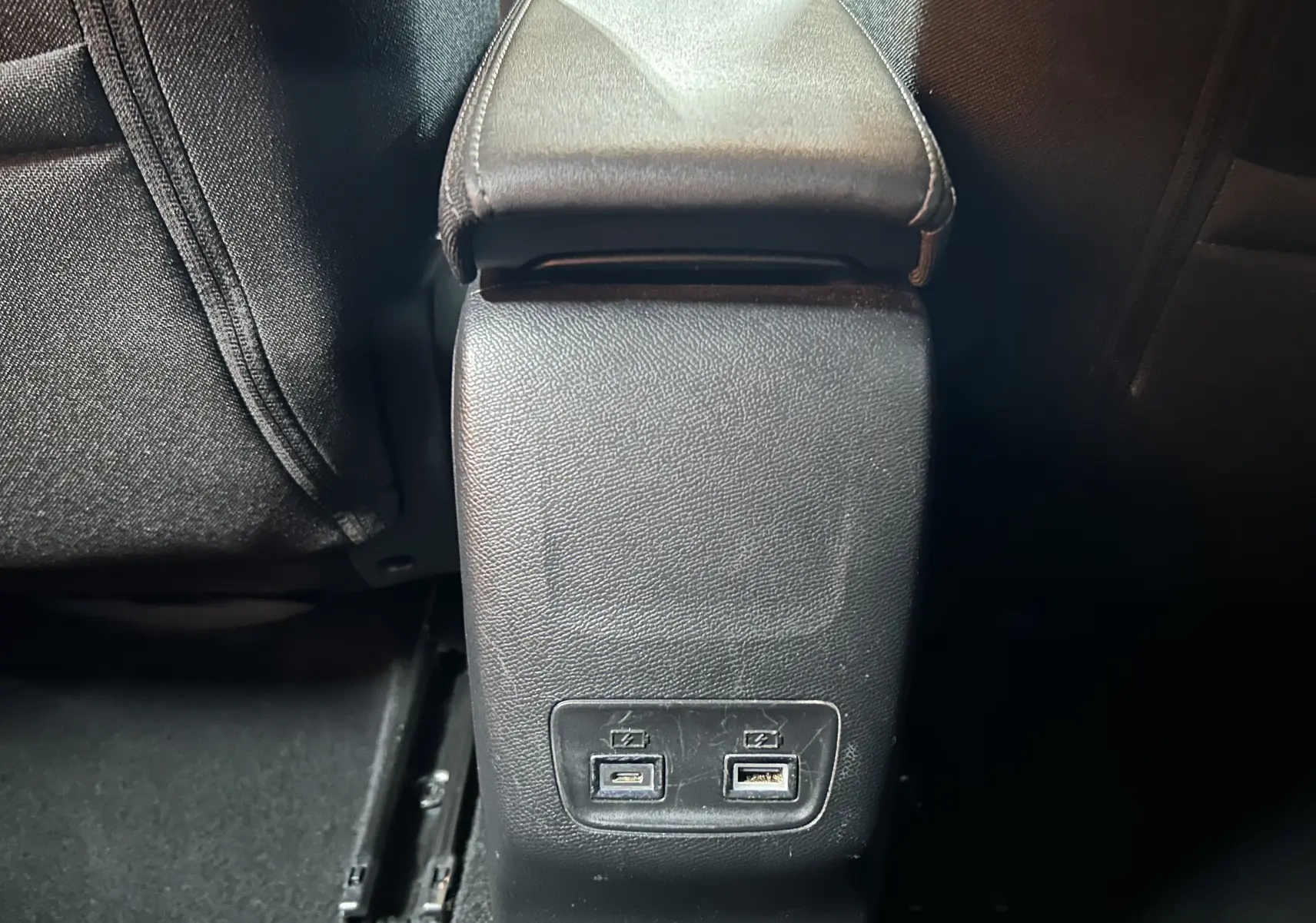 Vue rapprochée de la console centrale arrière noire avec deux ports USB sur la Peugeot 208 gris Selenium.