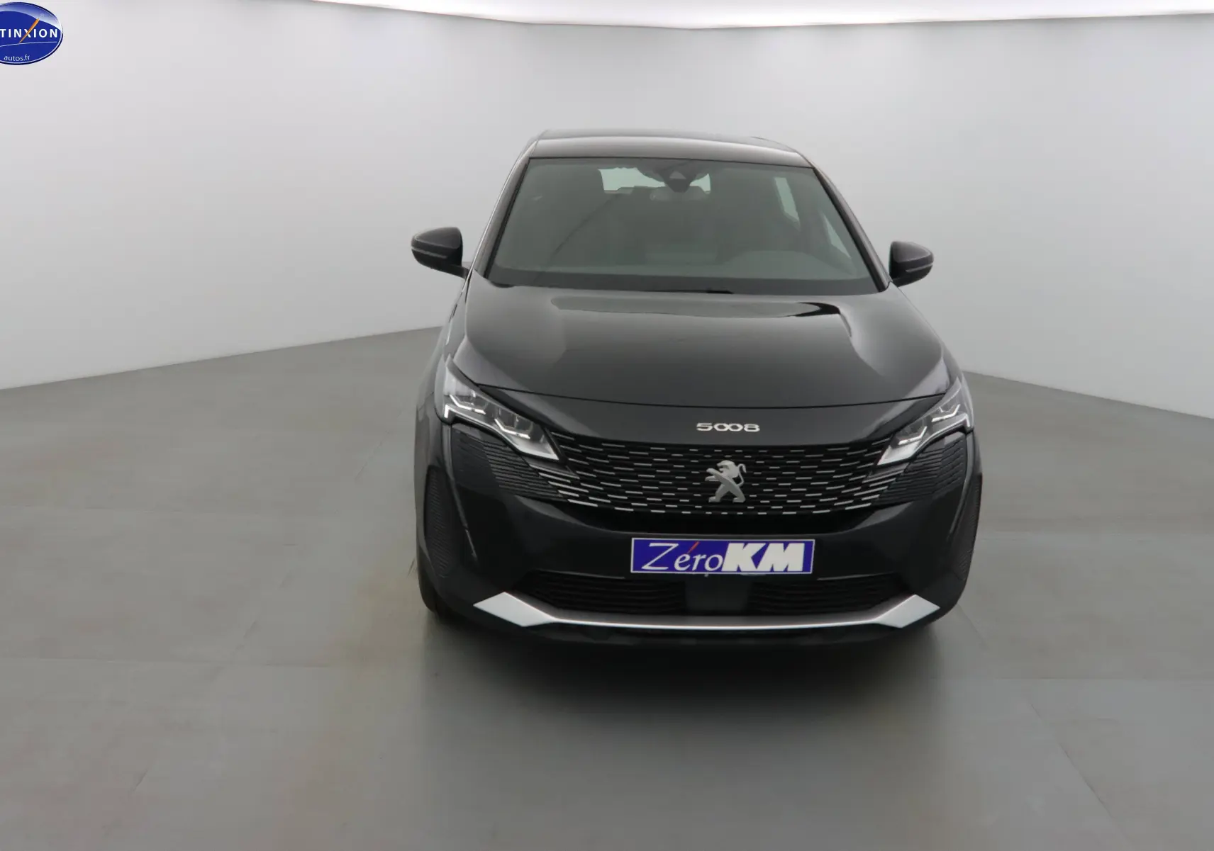 Peugeot 5008 noir perle métal vue de face dans un studio, mettant en valeur sa calandre distinctive et ses phares LED.