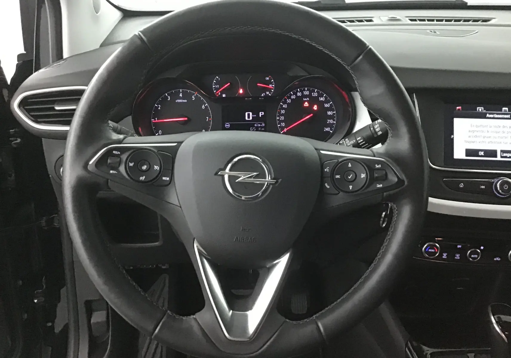 Vue intérieure centrée sur le volant noir de l'Opel Crossland 2022 avec tableau de bord et écran tactile visibles.